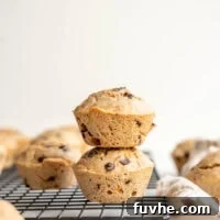 Two chocolate muffins stacked on a cooling rack.