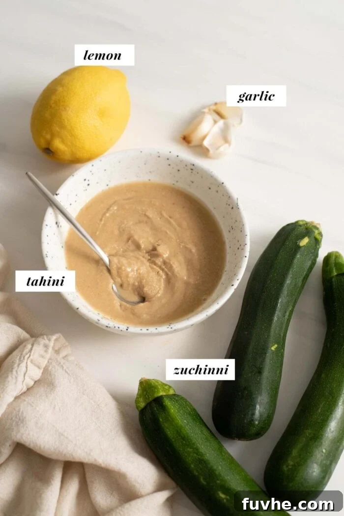 Fresh zucchini, creamy tahini, bright lemons, and aromatic garlic cloves arranged on a pristine marble surface, ready for blending into a delicious dip.