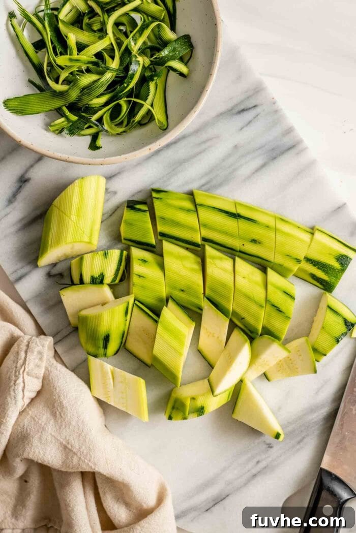 Peeled and roughly chopped zucchini chunks neatly arranged on a light marble cutting board, ready for blending.
