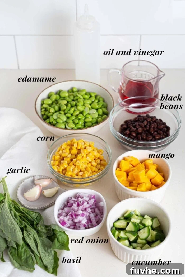 Tropical Mango Edamame Salad 3 Various labelled ingredients for a mango edamame salad in bowls on a counter, ready for preparation.