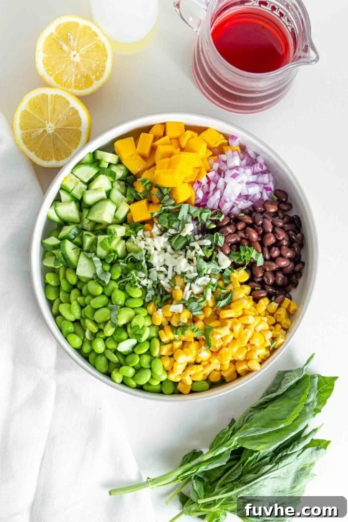 Tropical Mango Edamame Salad 5 Edamame, corn, mango, black beans and cucumber in a large mixing bowl, showing the assembled ingredients before dressing.