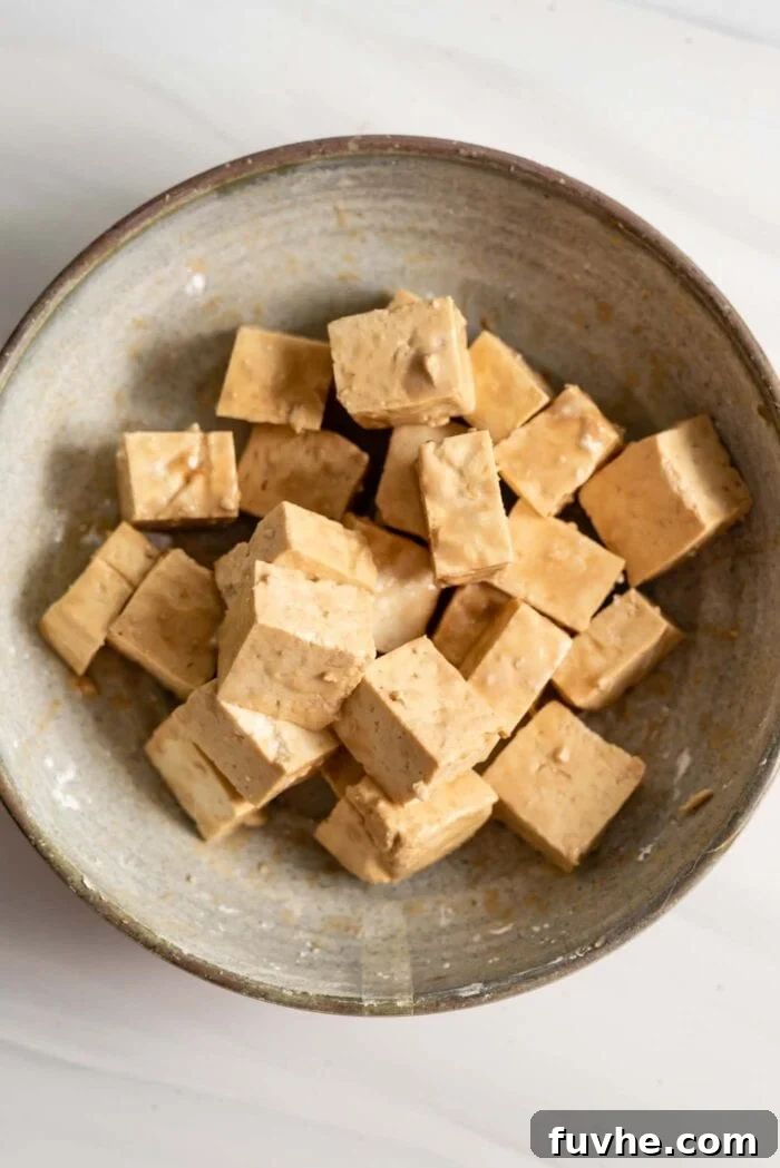 Tofu cubes coated in cornstarch and soy sauce, ready for frying.