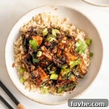 Black pepper tofu in a bowl with a pair of chopsticks beside it, ready to be eaten.