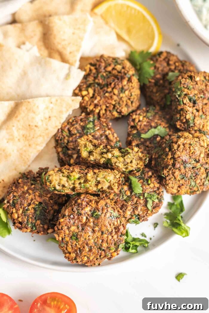 Golden Baked Falafel 12 A close-up of crispy baked falafel on a plate, with one patty broken open to reveal its tender, green interior.
