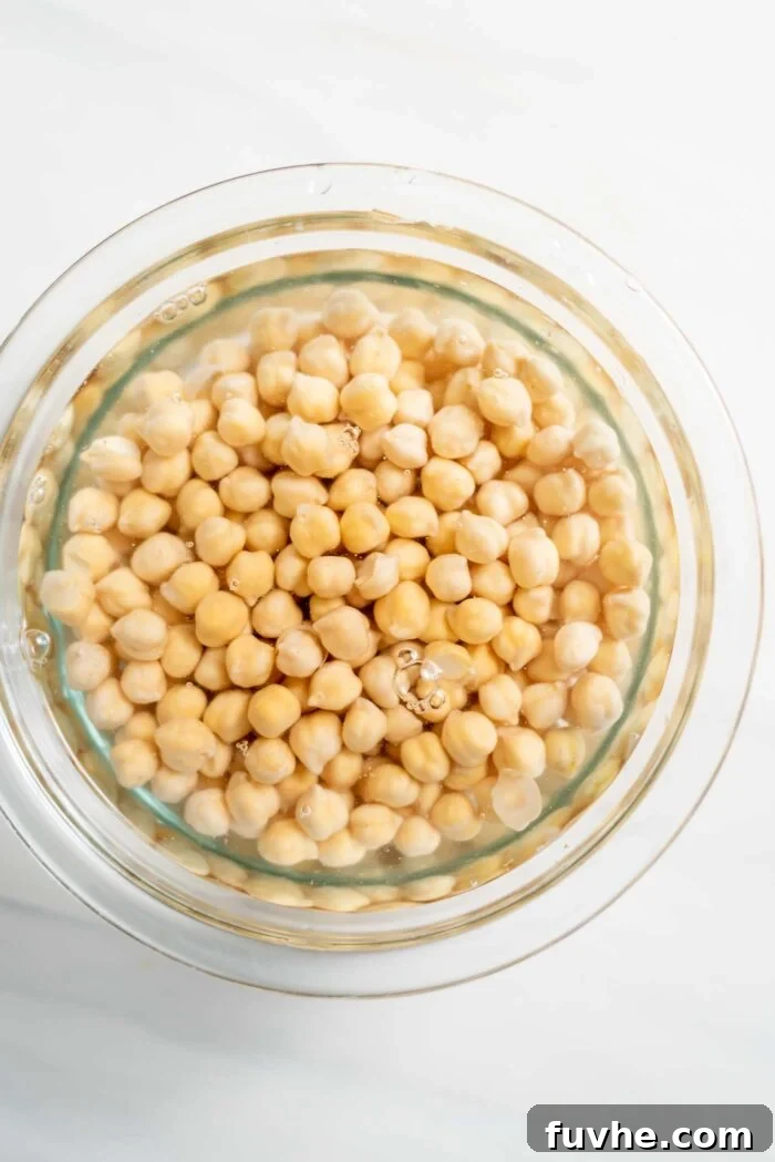 Golden Baked Falafel 3 Dry chickpeas soaking in a clear glass bowl of water, demonstrating their expansion.
