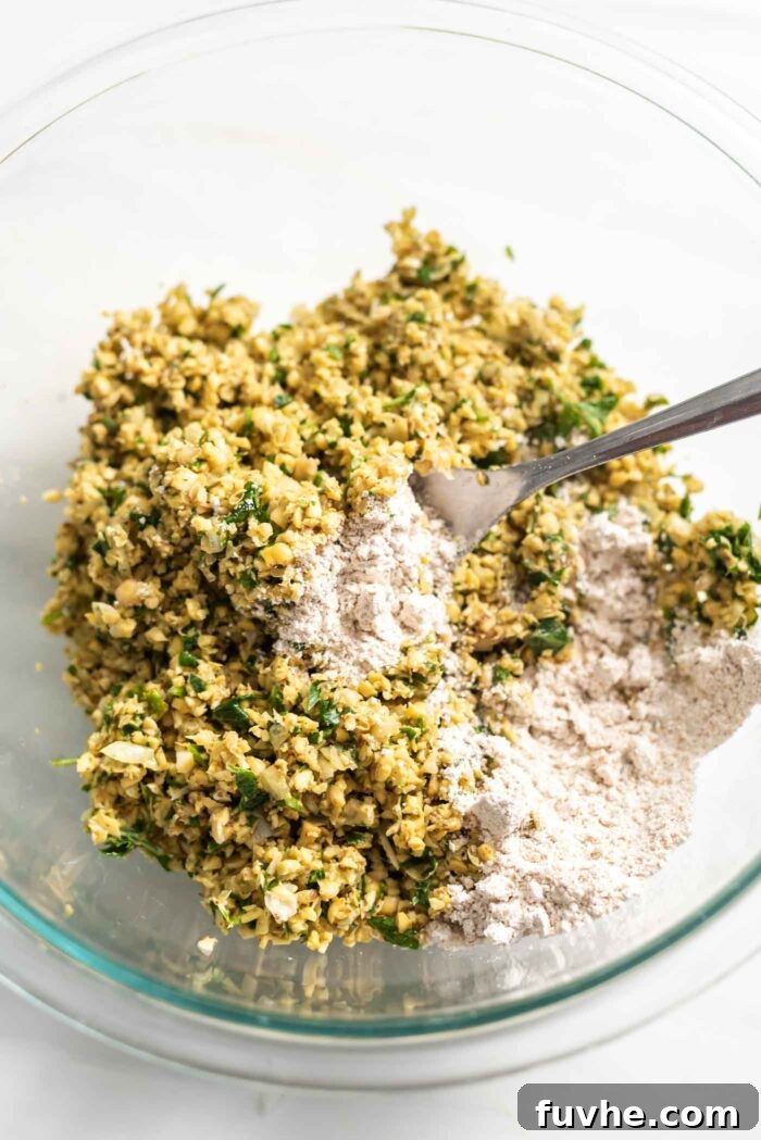 Golden Baked Falafel 8 Mixing flour into the falafel mixture in a clear glass bowl until well combined.