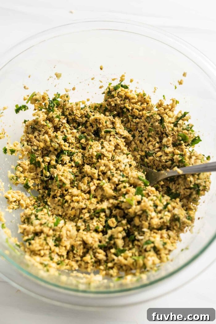Golden Baked Falafel 9 The raw falafel mixture, perfectly cohesive, resting in a glass bowl with a spoon.