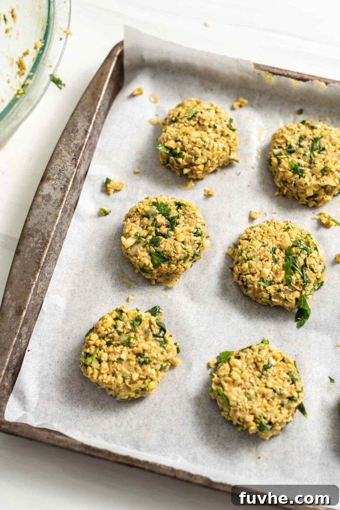 Golden Baked Falafel 10 Raw falafel patties meticulously arranged on a baking tray lined with parchment paper, ready for baking.