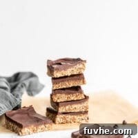 Stack of 5 chocolate covered coconut date bars on a piece of parchment paper.