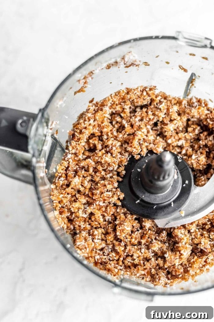 Decadent Plant-Based Chocolate Coconut Squares 4 Blended dough for chocolate coconut bars in a food processor, showing a coarse yet cohesive texture ready to be pressed.