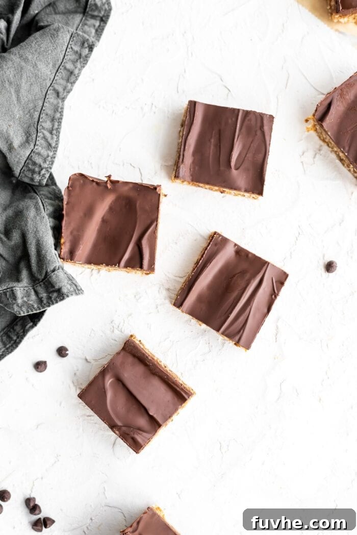 Decadent Plant-Based Chocolate Coconut Squares 10 Overhead shot of a few perfectly made chocolate coconut bars scattered on a rustic textured surface, emphasizing their deliciousness and rich layers.
