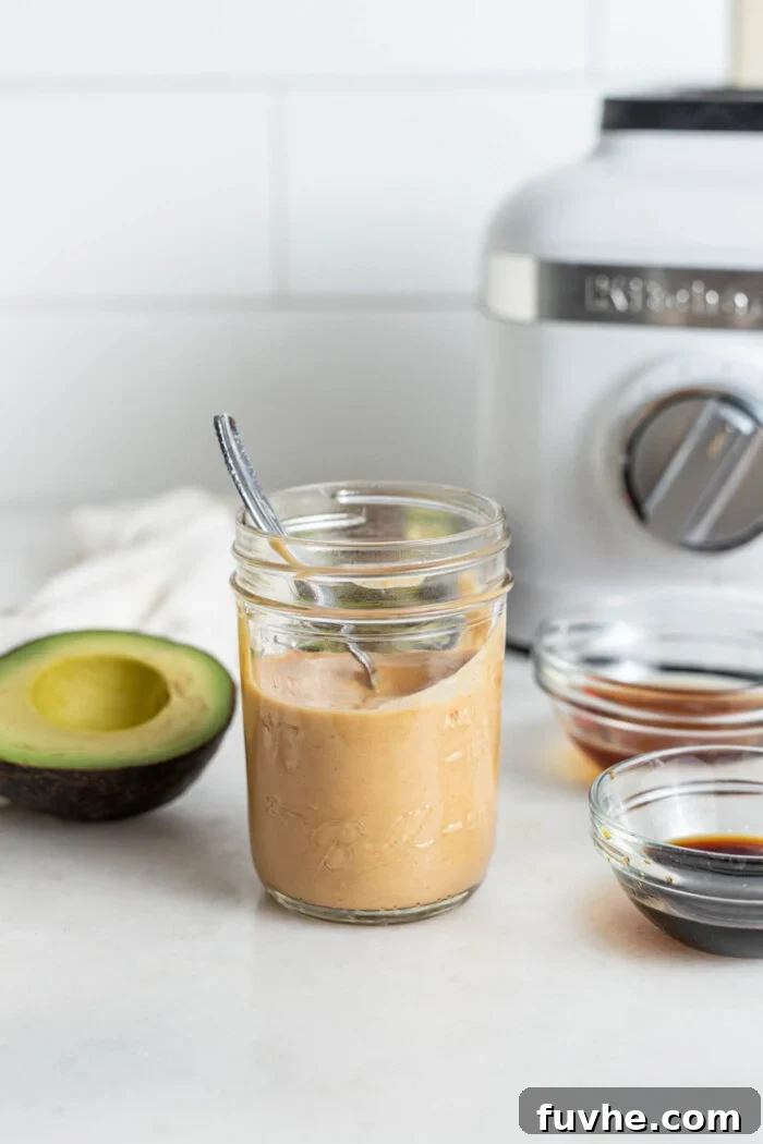 A charming jar filled with freshly blended vegan spicy mayo, with a spoon nestled inside, ready to be served.