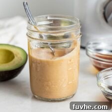 A charming jar filled with freshly blended vegan spicy mayo, with a spoon nestled inside, ready to be served.