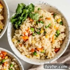 A bowl of rice pilaf with peas, corn and carrots and some cilantro on the side, highlighting a perfect serving of the Instant Pot dish.