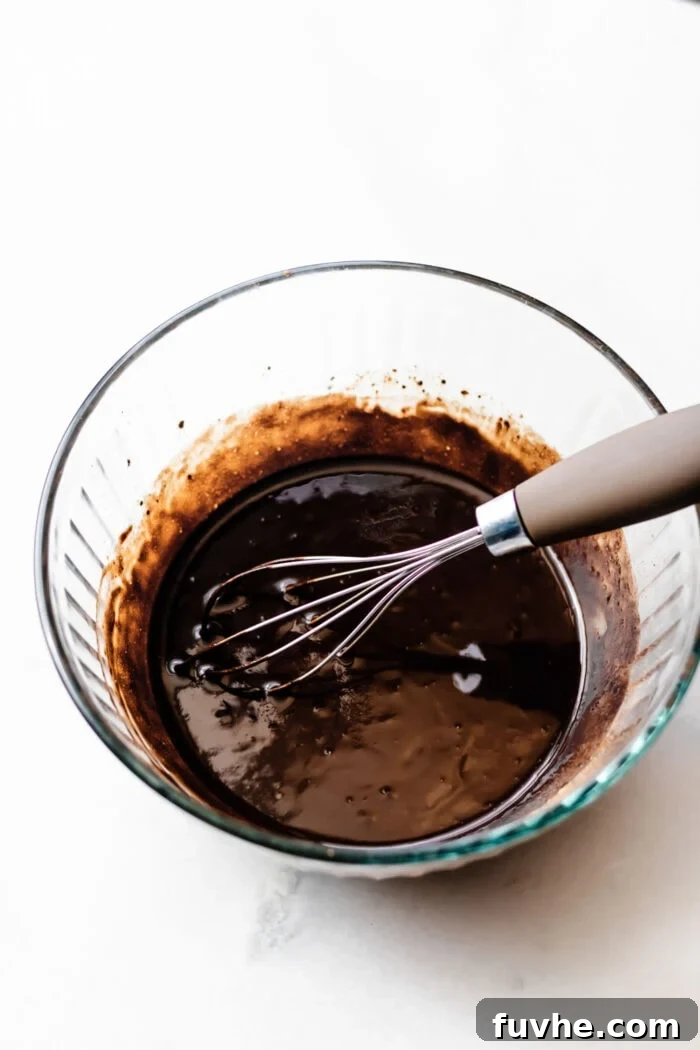 Mixed homemade vegan chocolate in a glass bowl with a whisk, ready for the first layer.
