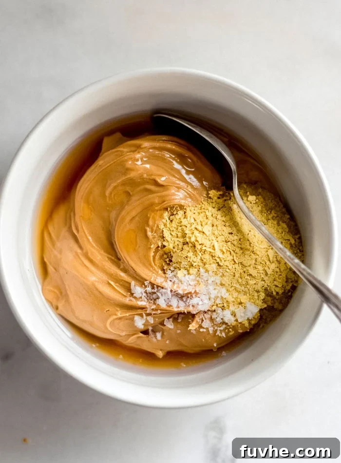 A bowl containing peanut butter, nutritional yeast, and coconut oil, ready to be mixed for the filling.