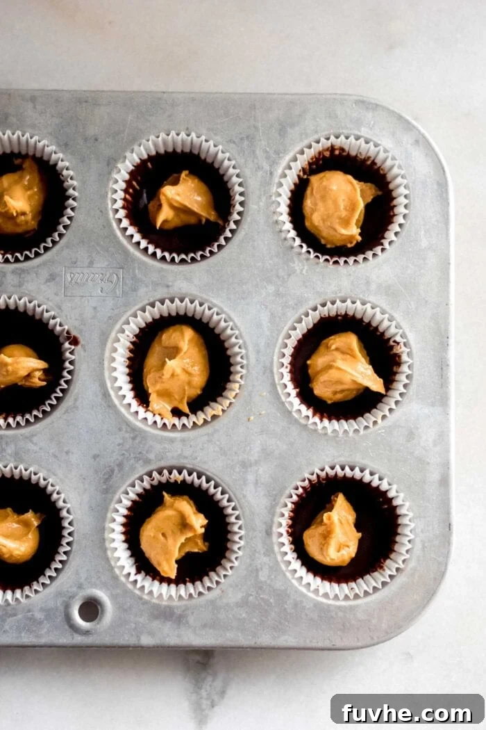Dollops of creamy peanut butter filling carefully spooned into a lined muffin tin.