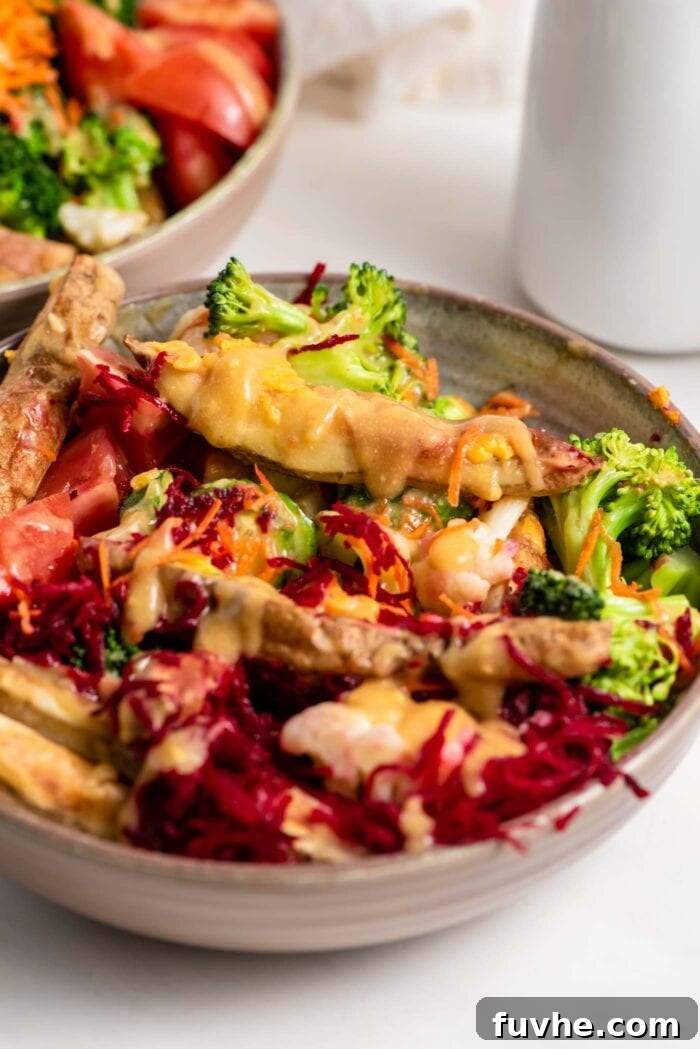 A beautifully composed bowl featuring golden roasted potatoes, vibrant grated beet and carrot, fresh cucumber slices, and juicy tomato, all drenched in a rich, creamy miso gravy.