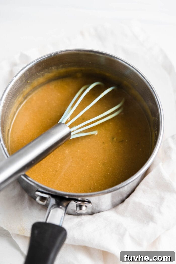 Thick, creamy miso gravy being whisked in a small saucepan on the stovetop.