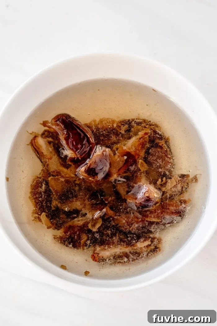 Pitted medjool dates soaking in a bowl of water.