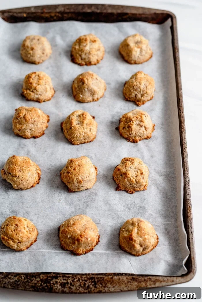 Baked coconut macaroons on a baking tray lined with parchment paper.