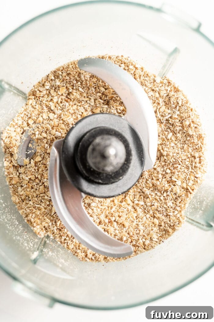 Rolled oats and walnuts are perfectly blended into a fine, grainy flour within a food processor, creating the foundational texture for the vegan meatloaf.
