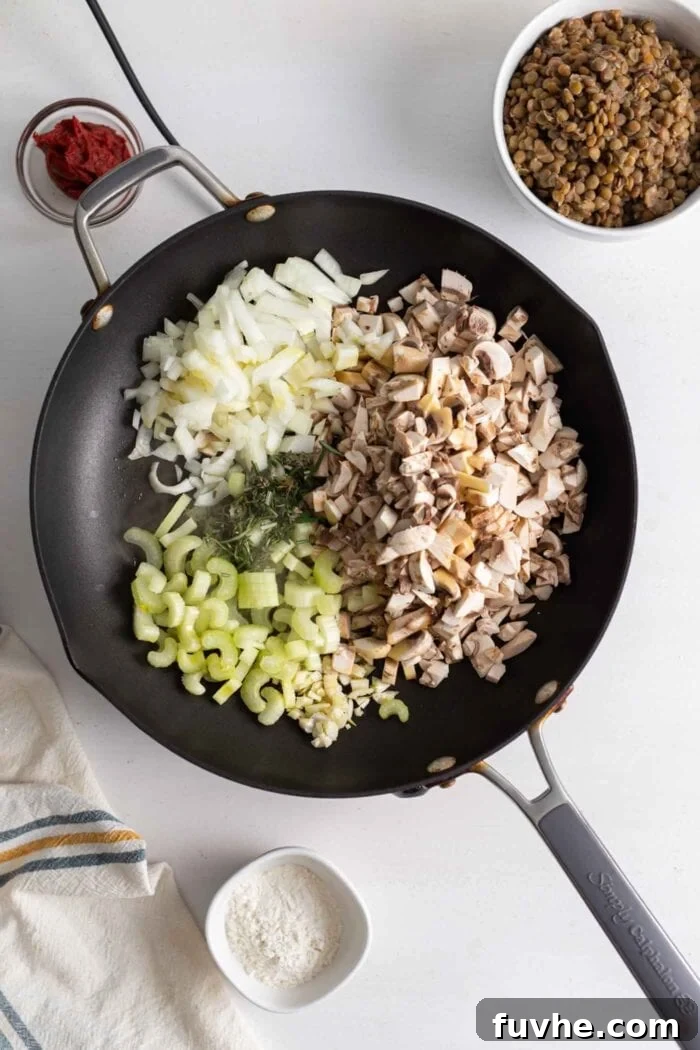 Comforting Vegan Lentil Shepherd's Pie 6 Finely chopped mushrooms, celery, and onions are sautéing in a large skillet on the stovetop, releasing their aromatic flavors.