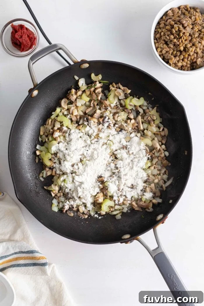Comforting Vegan Lentil Shepherd's Pie 7 A light dusting of flour has been sprinkled over the cooked vegetables in a skillet, ready to be stirred in to create a roux.