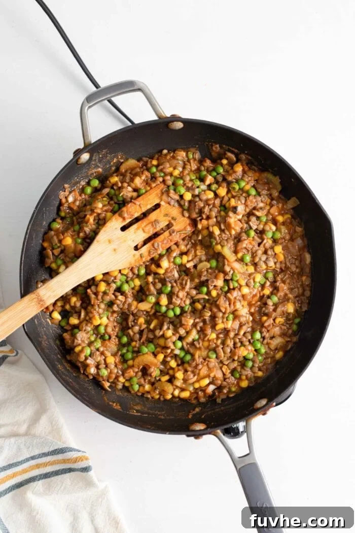 Comforting Vegan Lentil Shepherd's Pie 9 A rich, cooked filling for a lentil shepherd's pie, brimming with vegetables and lentils, is simmering in a skillet, ready for assembly.