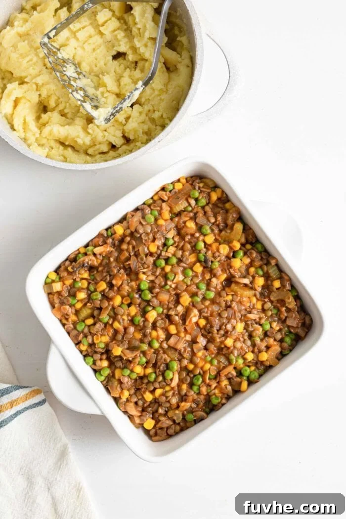 Comforting Vegan Lentil Shepherd's Pie 10 A vibrant lentil and vegetable mixture, the base of a shepherd's pie, evenly spread in a 9x13-inch baking dish, awaiting its potato topping.