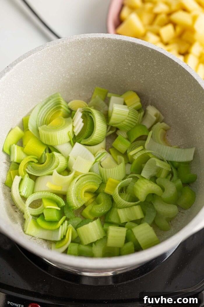 Creamy Vegan Potato Leek Soup 4 Celery, leek, garlic, and onion gently cooking in a pot on a stovetop, forming the aromatic foundation for the soup.