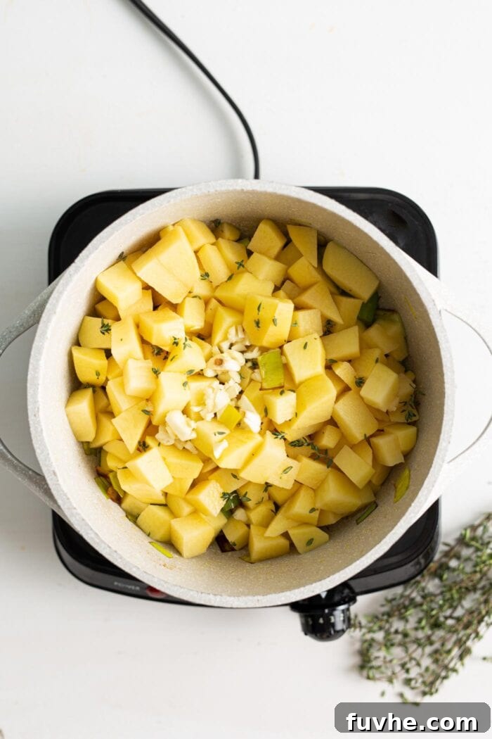 Creamy Vegan Potato Leek Soup 5 Diced potatoes being added to the pot, mingling with the sautéed aromatics, ready for the next stage of cooking.