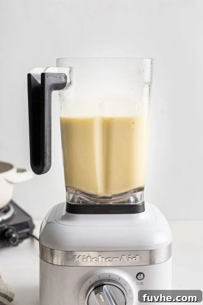 Creamy Vegan Potato Leek Soup 7 Smooth, blended potato leek soup swirling inside a white Kitchenaid blender, demonstrating its creamy texture.