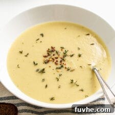 Creamy potato leek soup in a bowl topped with rosemary and red pepper flakes.