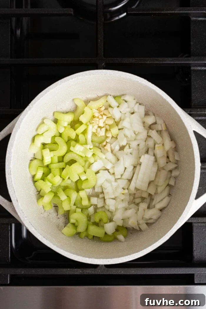 Nourishing Tuscan Kale and White Bean Soup 4 Onions, garlic and celery cooking in a large soup pot on a gas range stove.