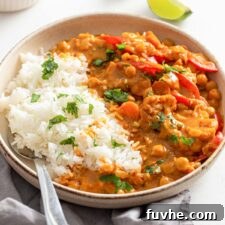 Bowl of rice with cauliflower chickpea curry topped with a sprinkle of fresh cilantro. Spoon rests in bowl.