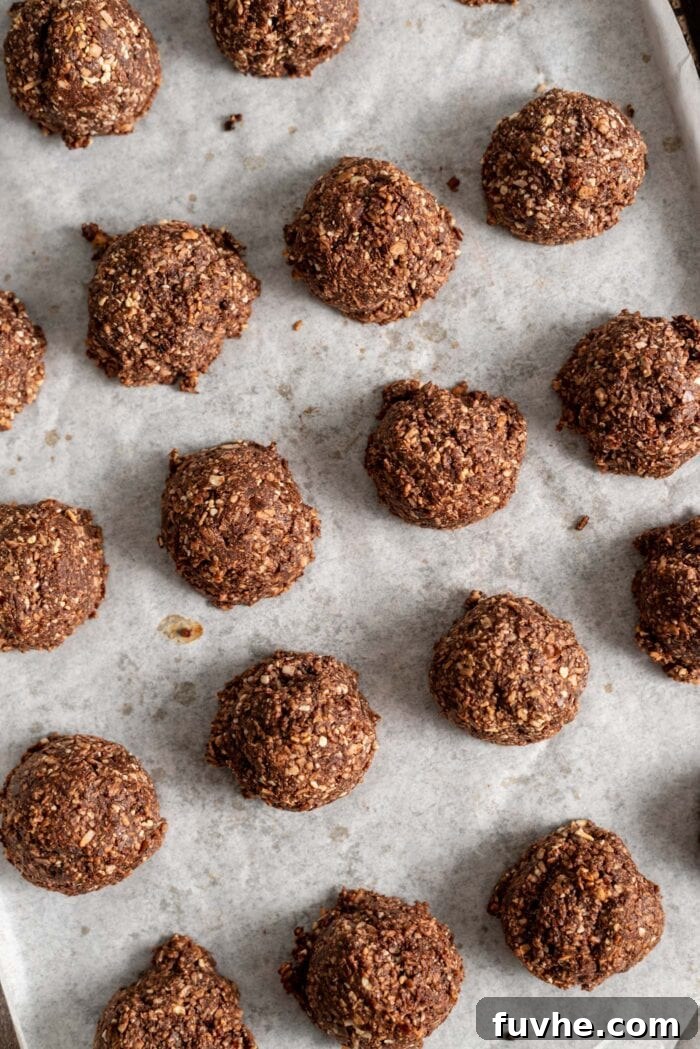 Decadent Vegan Chocolate Macarons 8 Baked chocolate macaroons on a parchment paper-lined baking tray.