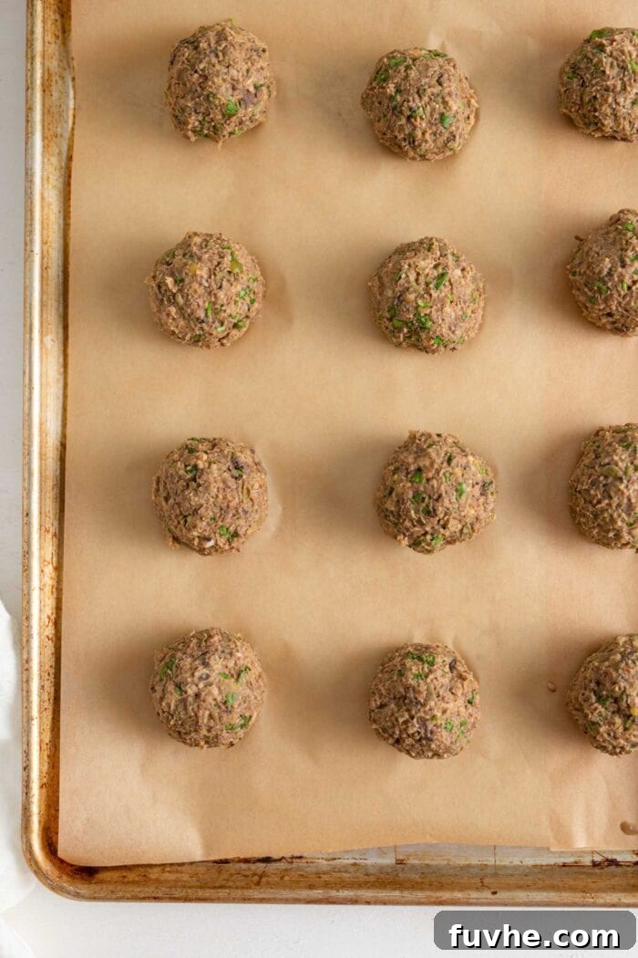 Savory Lentil Plantballs 8 A baking tray lined with parchment paper, neatly arranged with freshly rolled lentil meatballs, ready for the oven.
