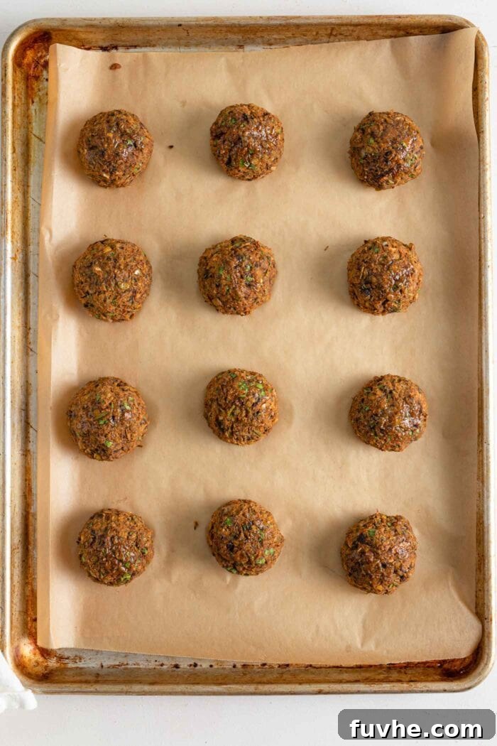 Savory Lentil Plantballs 9 A close-up of perfectly baked golden-brown lentil meatballs resting on a parchment-lined baking tray, fresh from the oven.