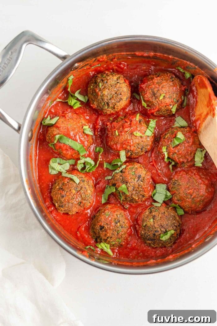 Savory Lentil Plantballs 10 A large skillet brimming with simmering lentil meatballs generously coated in a rich, vibrant tomato sauce, ready to be served.