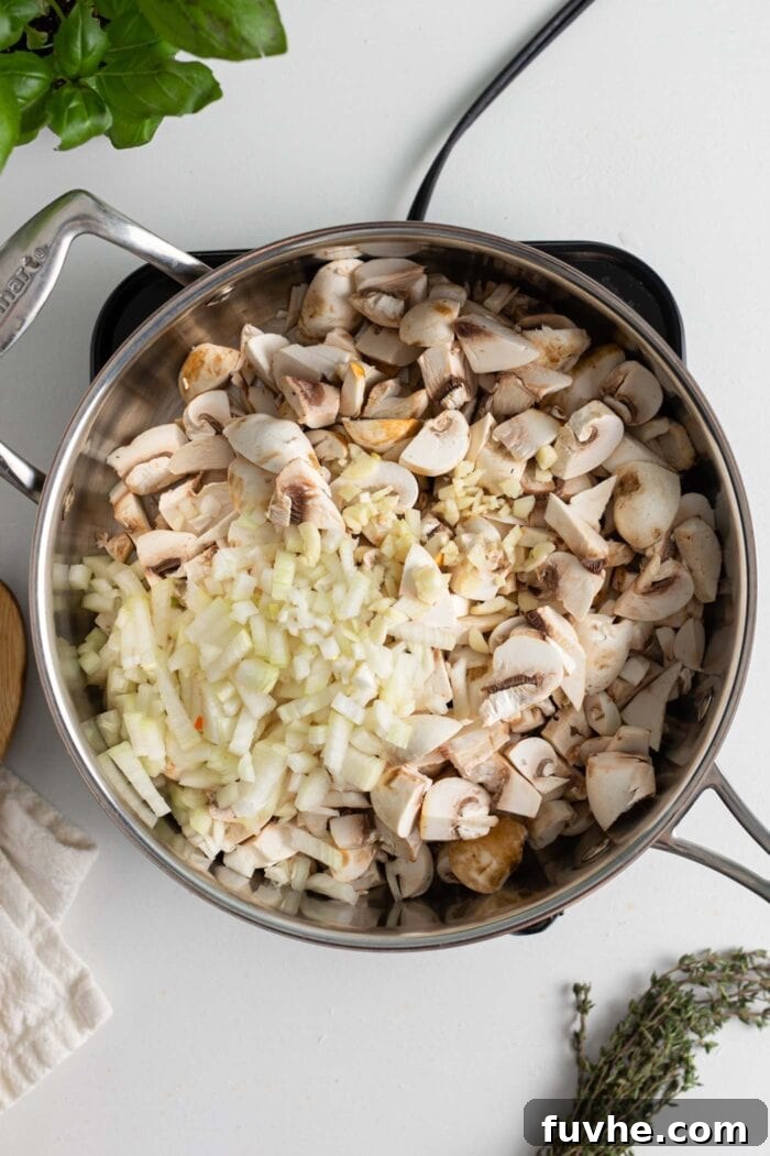 Hearty Vegan Mushroom Bolognese 4 Diced mushrooms, onion and garlic cooking in a skillet on a small induction cooktop.