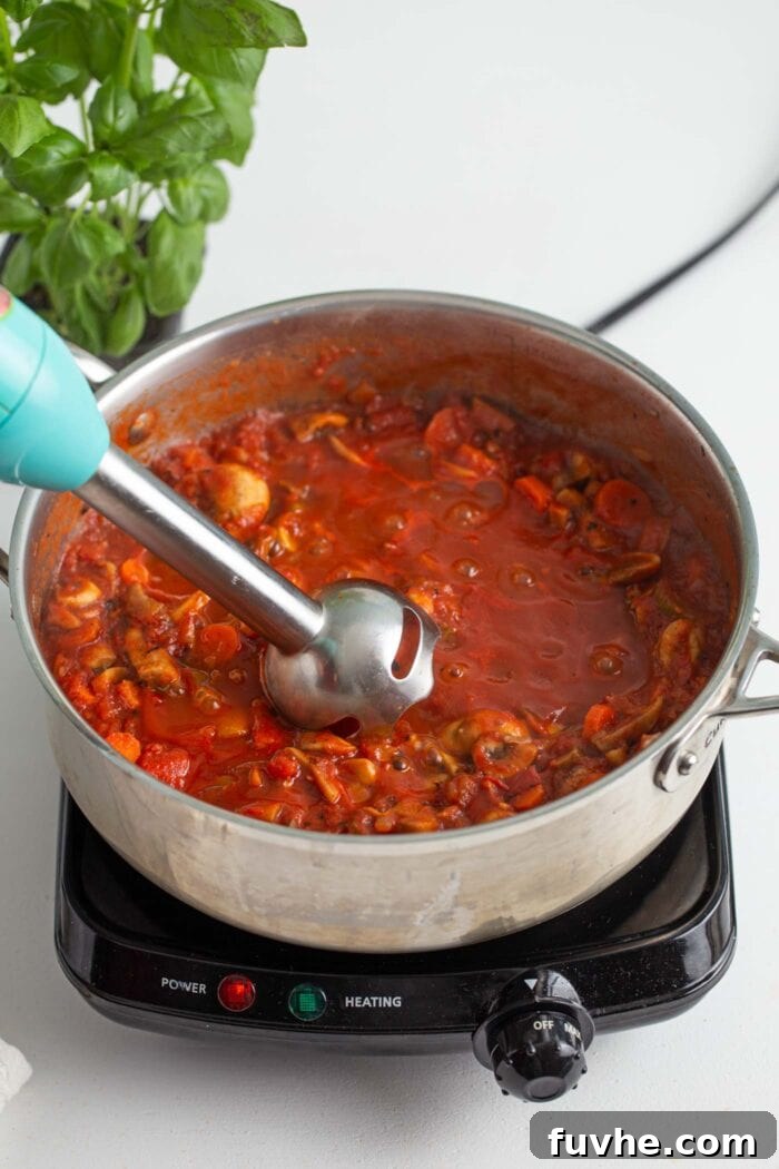 Hearty Vegan Mushroom Bolognese 7 Immersion blender in a pot of vegan mushroom bolognese sauce.