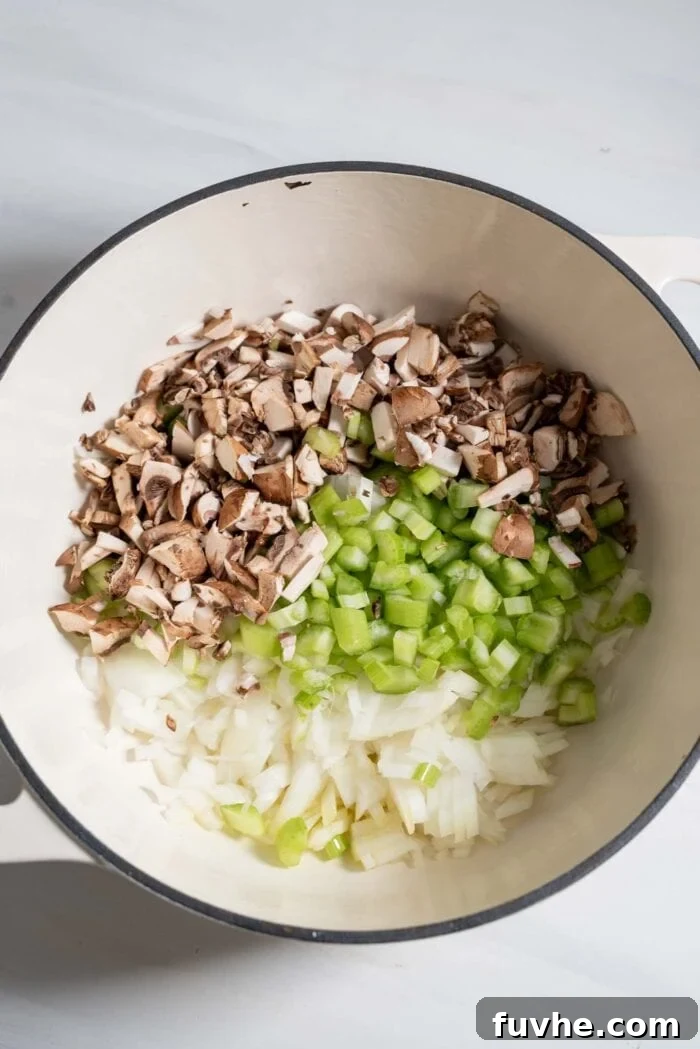 Finely chopped mushrooms, celery, onion, and garlic ready to be sautéed in a large saucepan.