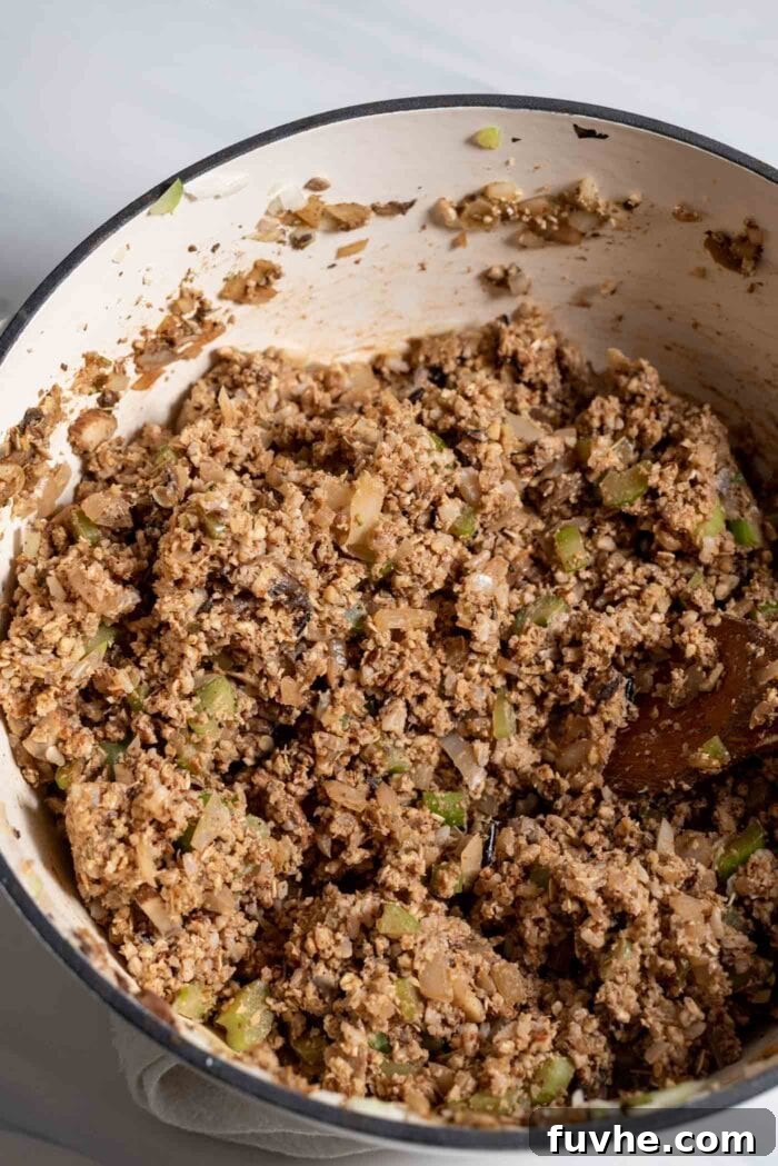 The raw vegan nut roast mixture, a rich blend of vegetables, nuts, oats, and rice, thoroughly mixed in a large pot.