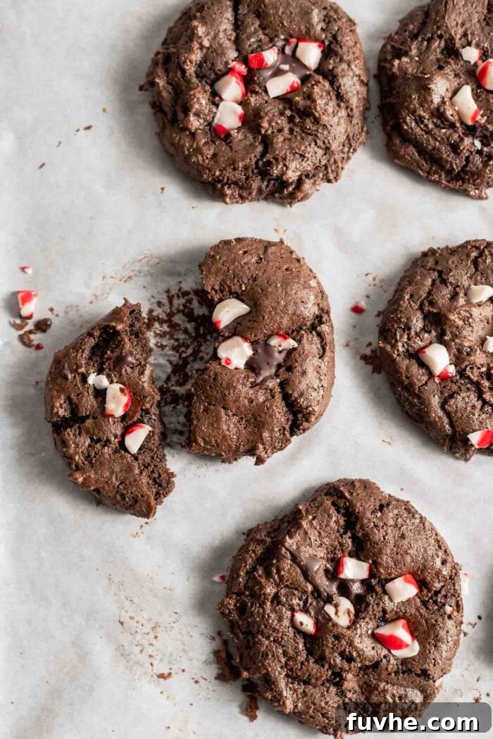 Irresistible Vegan Chocolate Peppermint Delights 8 Freshly baked vegan chocolate peppermint cookies on a baking tray, adorned with sparkling crushed candy canes.
