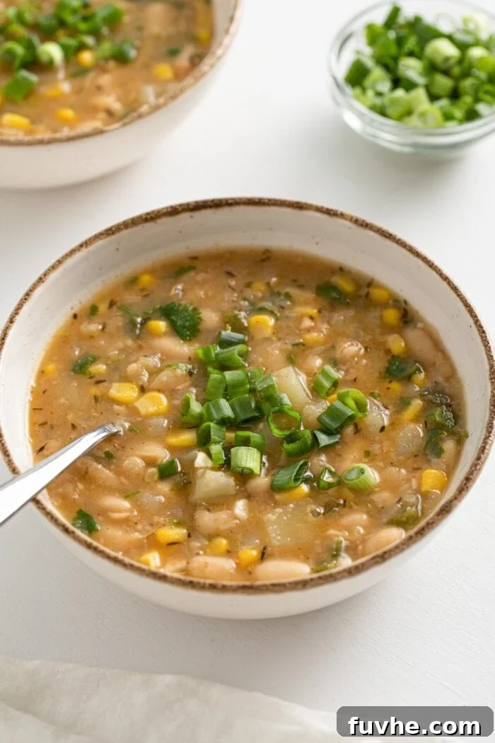 Creamy Vegan White Bean Chili 11 Bowl of white bean and potato chili topped with sliced scallions, beautifully garnished.