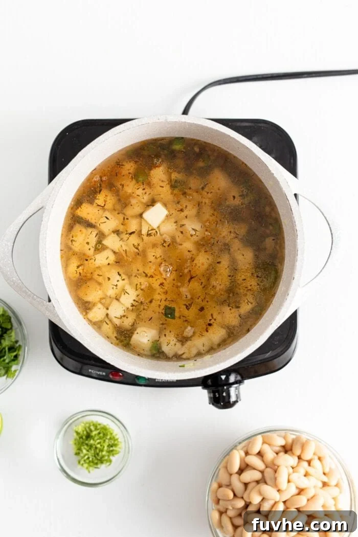 Creamy Vegan White Bean Chili 6 Diced potatoes cooking in broth in a large soup pot, simmering gently.