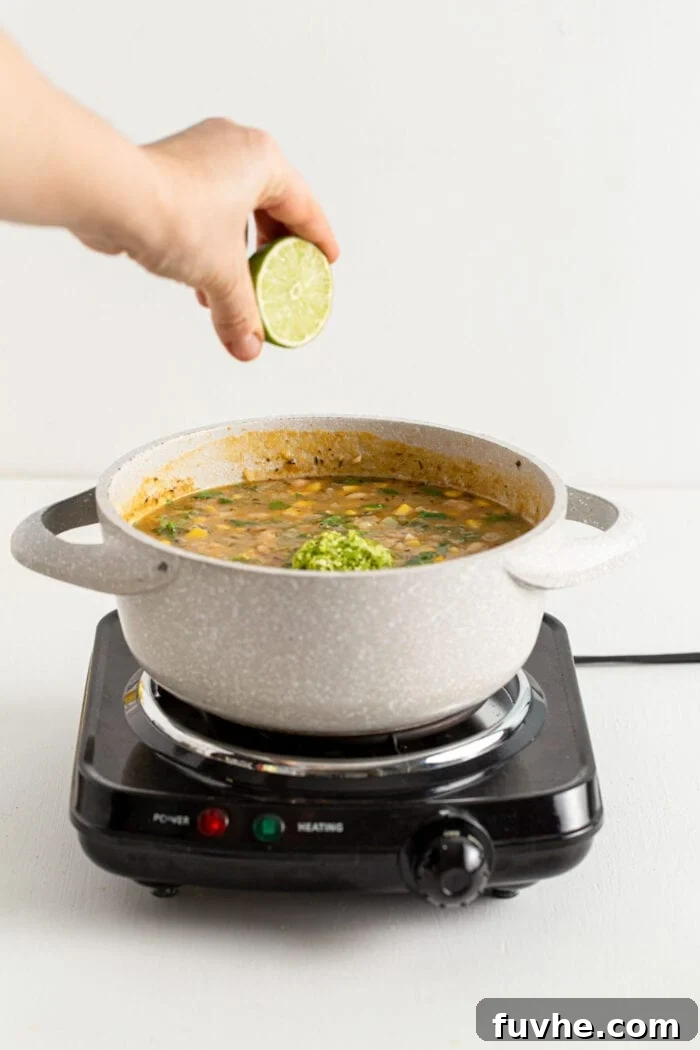 Creamy Vegan White Bean Chili 10 Squeezing lime into a pot of white bean chili, adding a zesty finish.