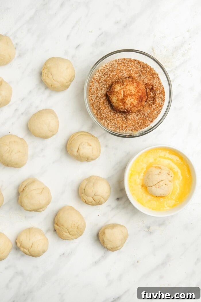 Small balls of vegan dough being rolled first in melted butter, then in a cinnamon sugar coating.