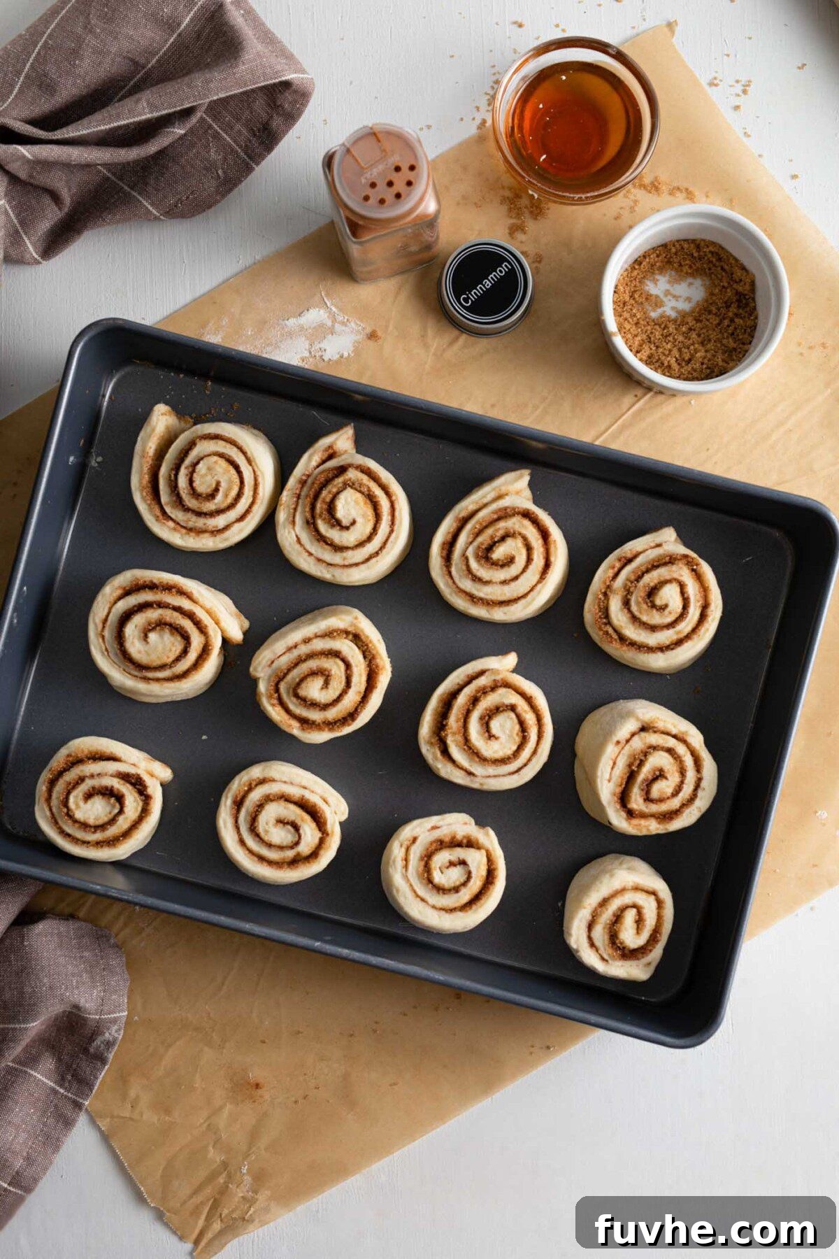 Raw, unbaked cinnamon rolls arranged in a 9x13 inch baking pan, ready for their final proof and baking.